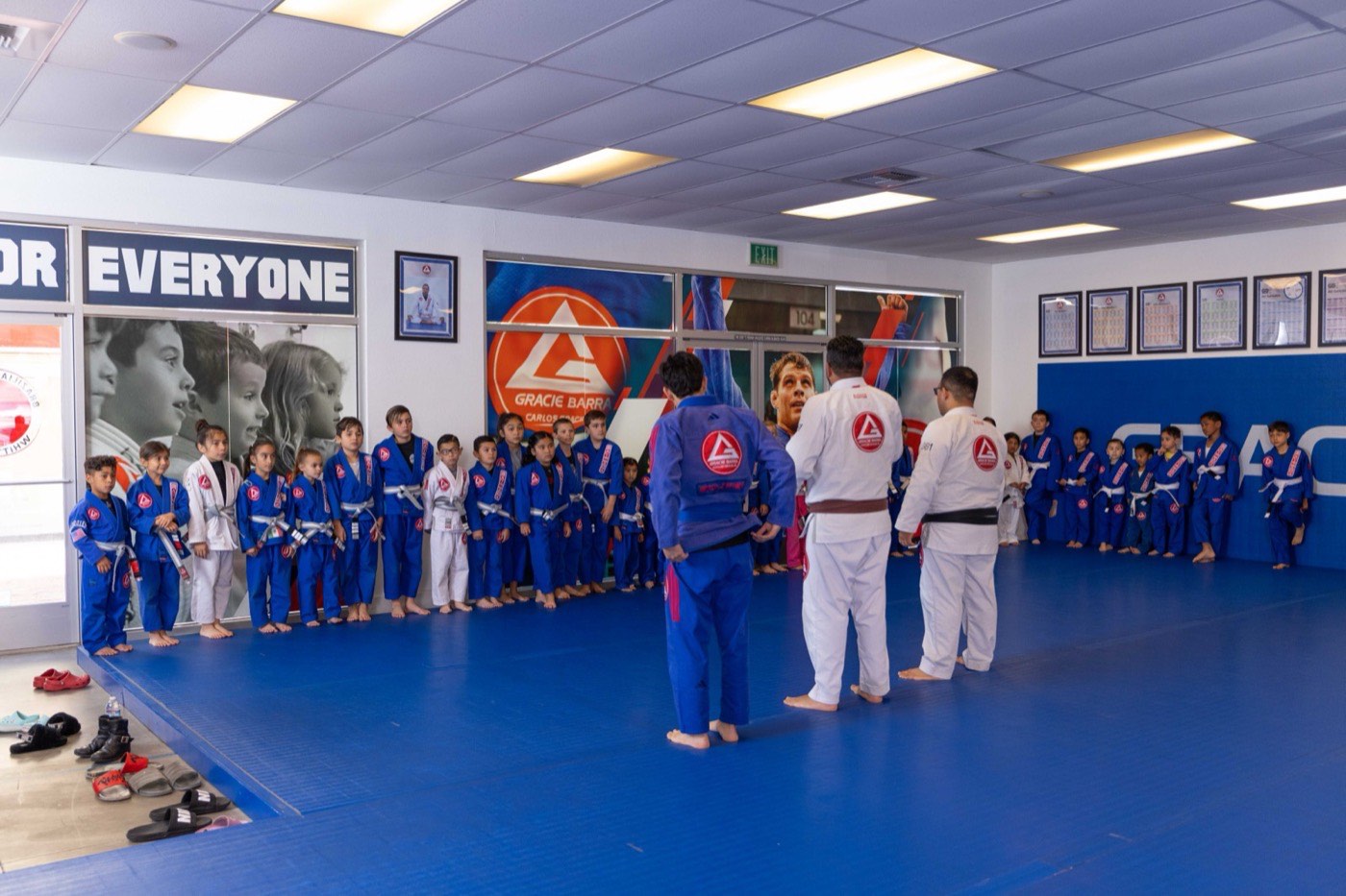 A full kids class lined up around the mat facing their instructors