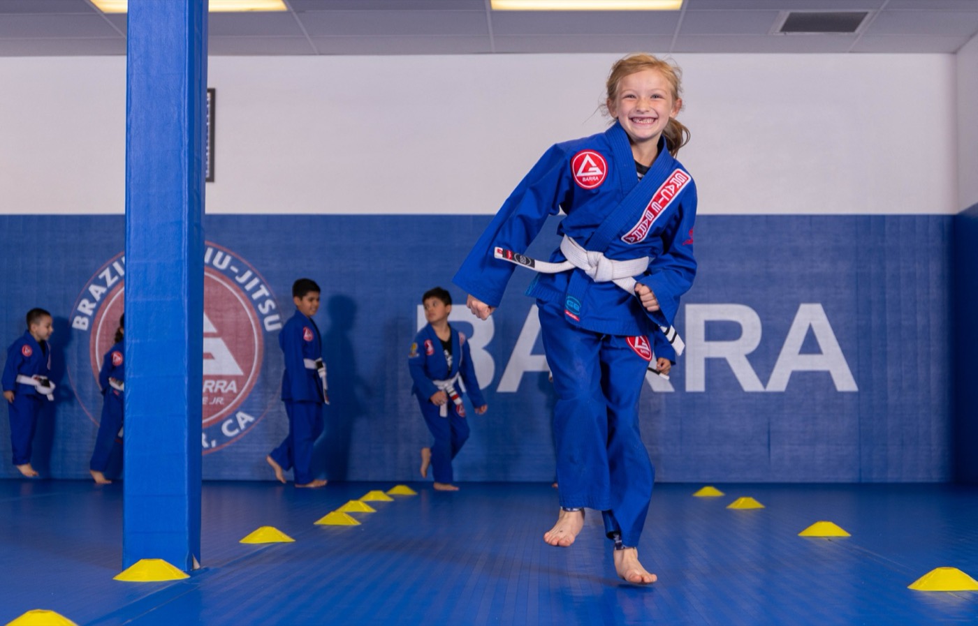 A girl runs toward the camera grinning during a drill