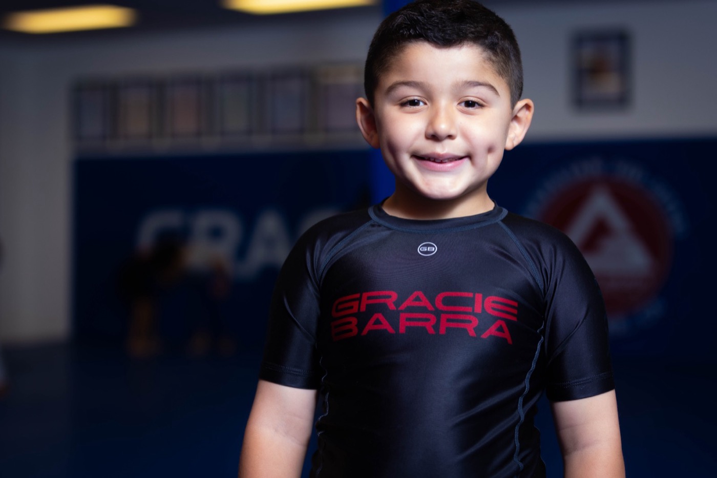A young student smiles at the camera on the mat